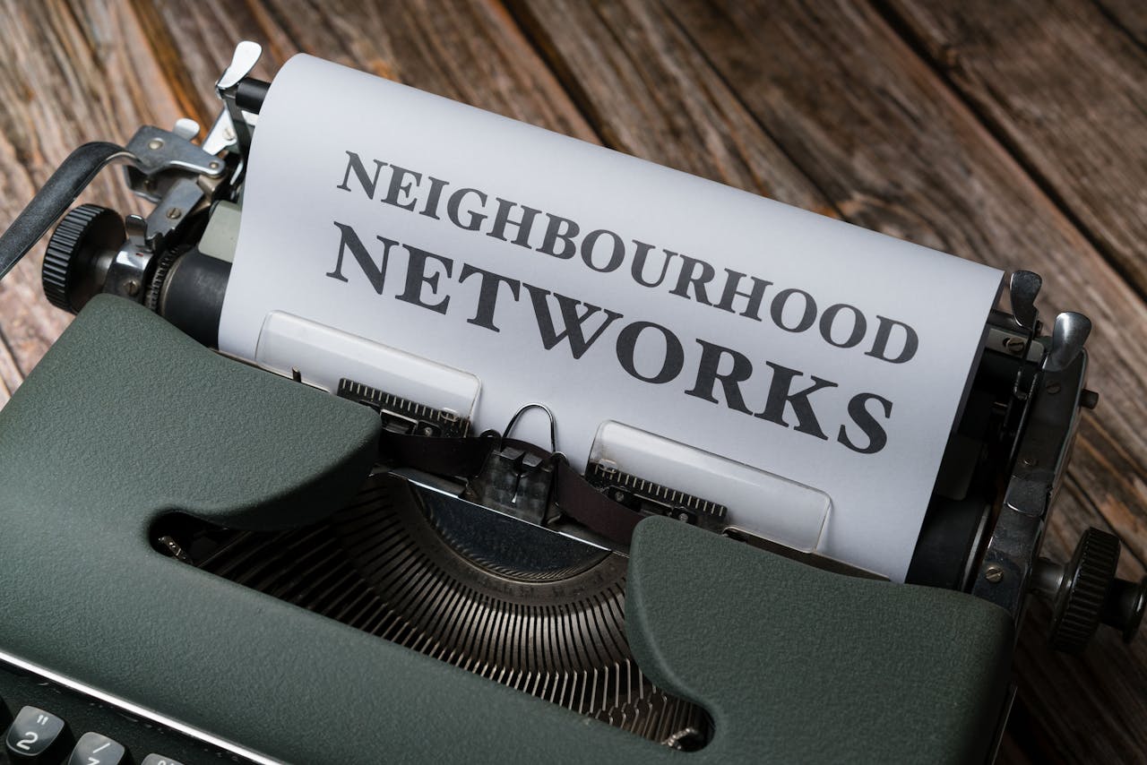 A vintage typewriter displaying the text Neighbourhood Networks on a wooden desk.